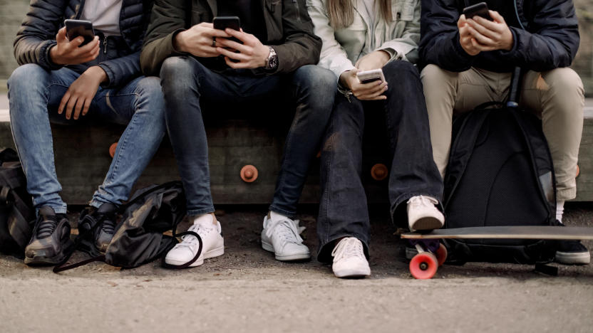 Low section of teenage boys and girl using smart phone while sitting at park