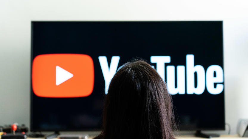 A woman seen sitting in front of a tv screen that  shows the logo of You Tube platform. (Photo by Nikos Pekiaridis/NurPhoto via Getty Images)