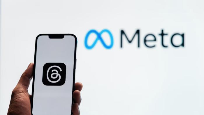 Logo on a phone with Meta sign in background.