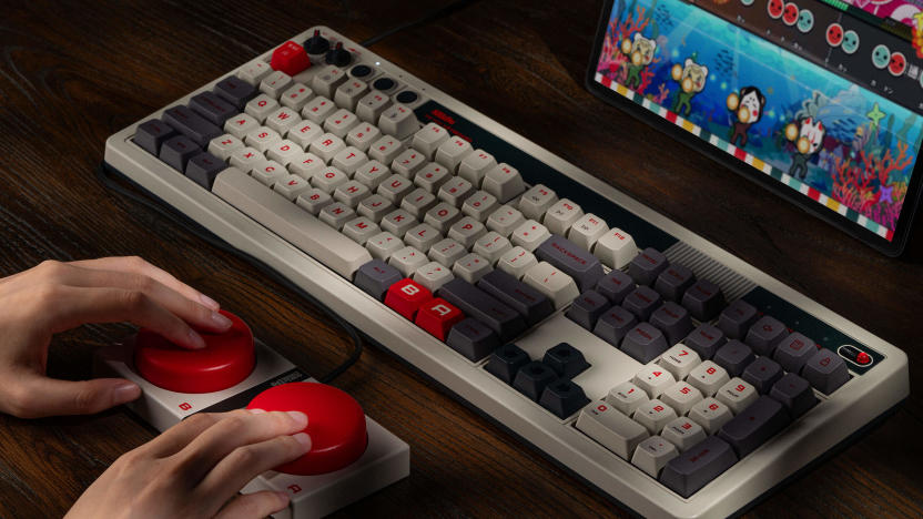 Product lifestyle photo of the 8BitDo Retro 108 Mechanical Keyboard. A person is mashing two big red buttons beneath the keyboard.